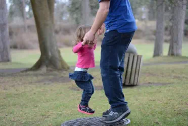 Vater spielt mit seinem Kind auf einer Wiese im Park