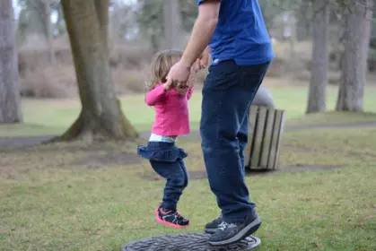 Vater spielt mit seinem Kind auf einer Wiese im Park