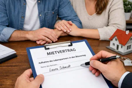 „Formular zur Aufnahme eines Lebenspartners in einen Mietvertrag wird ausgefüllt, im Hintergrund sitzt ein Paar.“